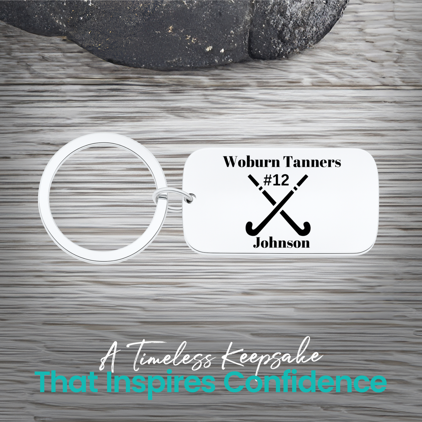 Stainless steel field hockey dog tag keychain with crossed sticks and personalized engraving on rustic wood