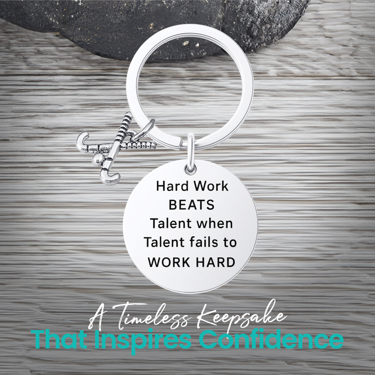 Silver field hockey keychain with engraved Work Hard Beats Talent charm on rustic wooden surface