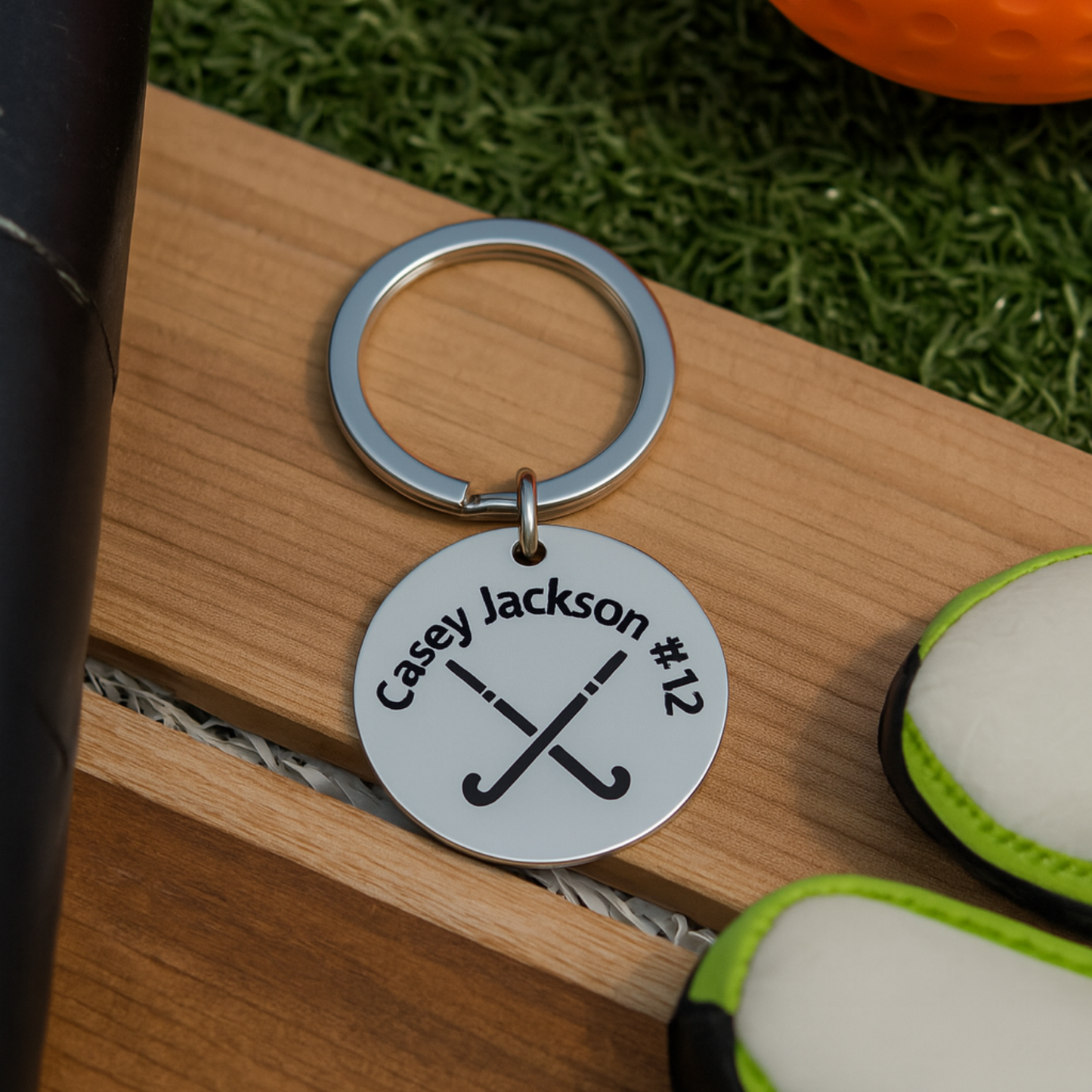 Personalized field hockey stick keychain displayed on turf with ball and stick in sports setting