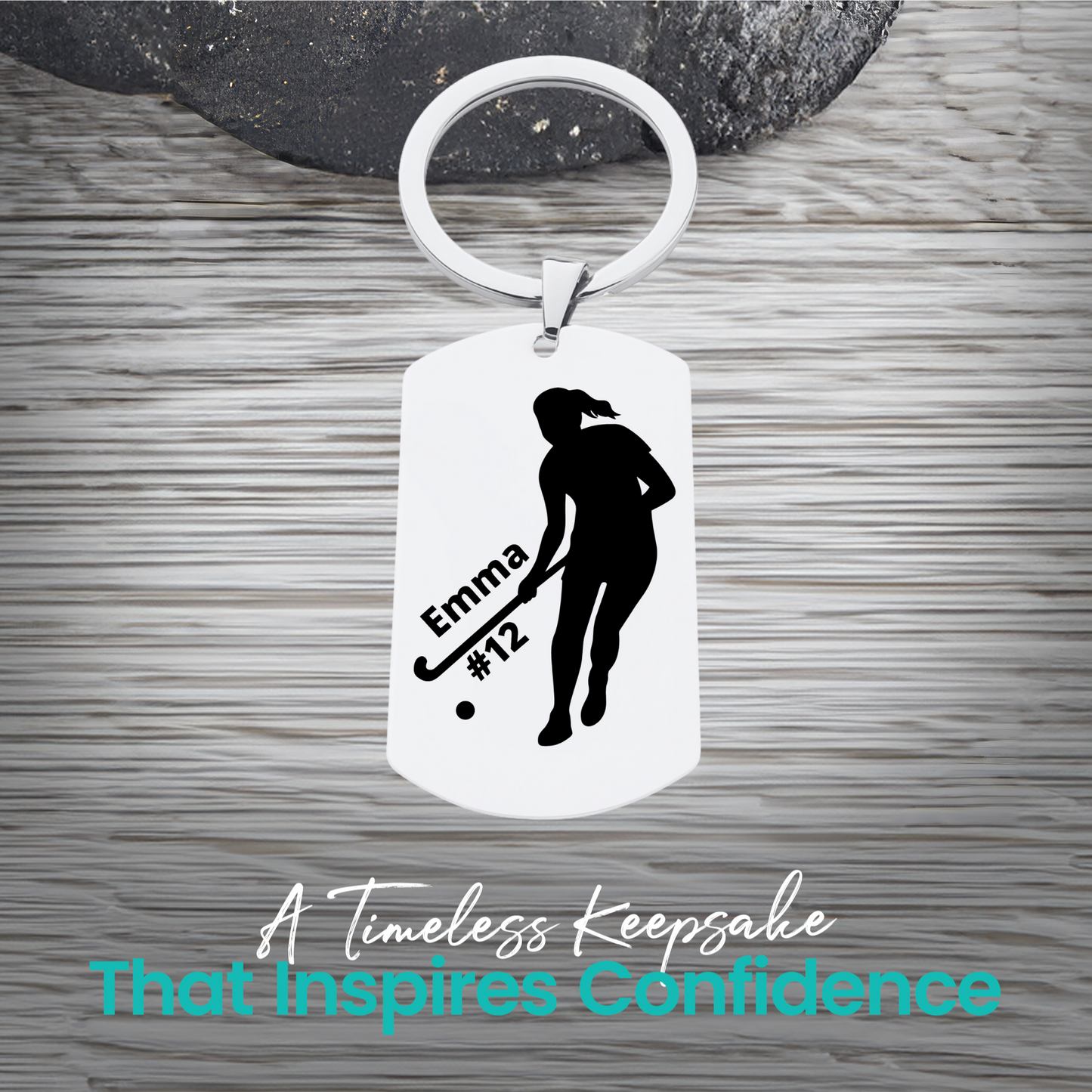 Engraved stainless steel field hockey player silhouette keychain with personalized text on rustic wood surface