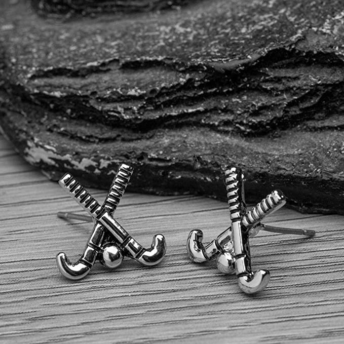 Silver and rose gold field hockey earrings placed on textured black rock for sporty display