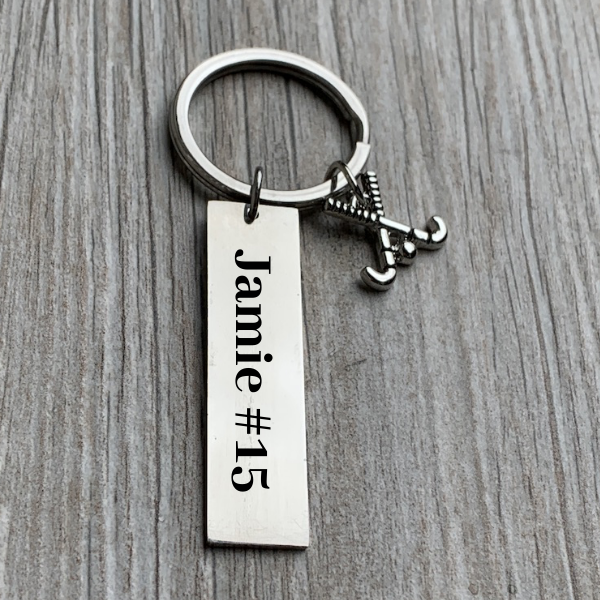 Custom engraved name bar field hockey keychain on gray wood surface
