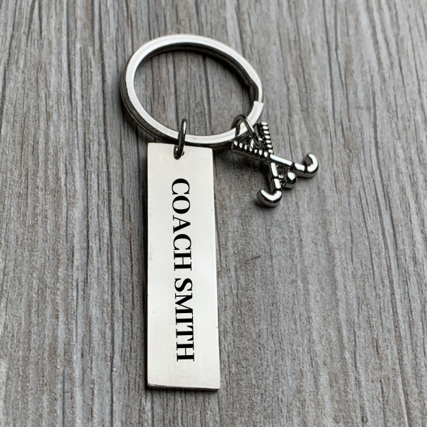 Close-up of engraved bar keychain with custom name on gray wood table