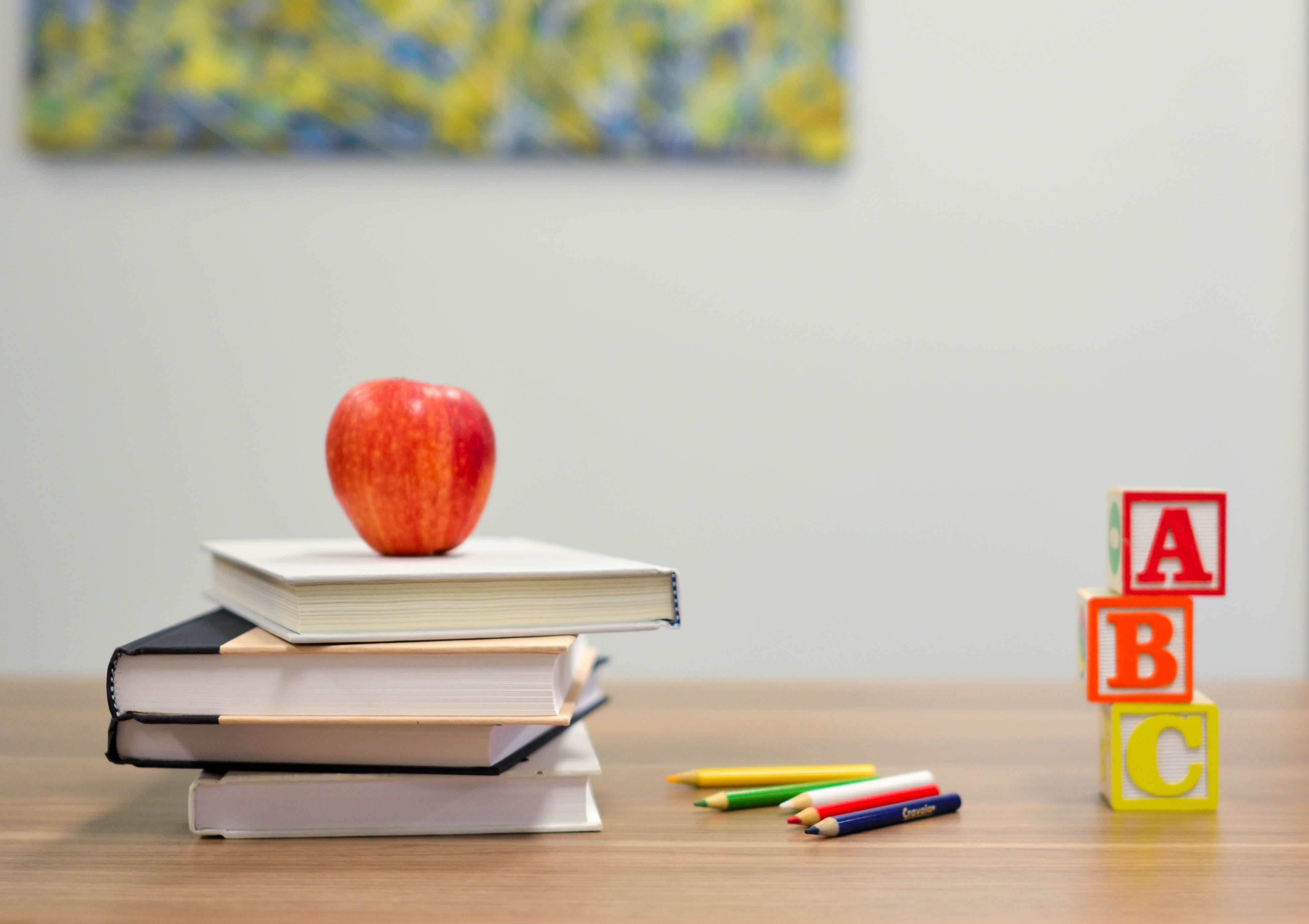 An Apple, Books, and Pencils on the School Desk in the Classroom
