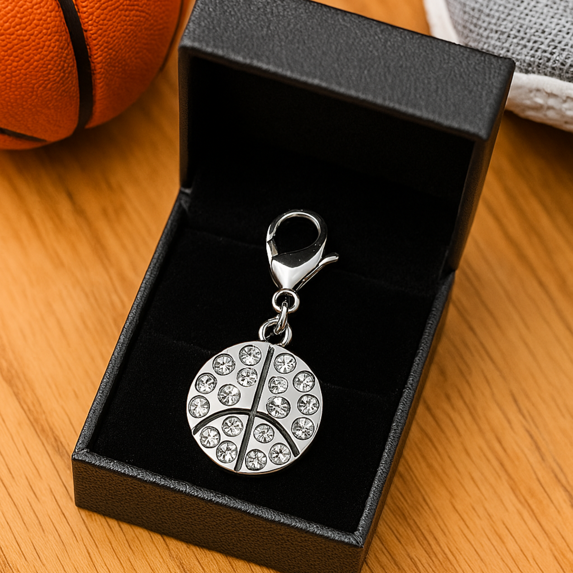 Clip-on basketball charm shown in black box with court lines engraved on charm