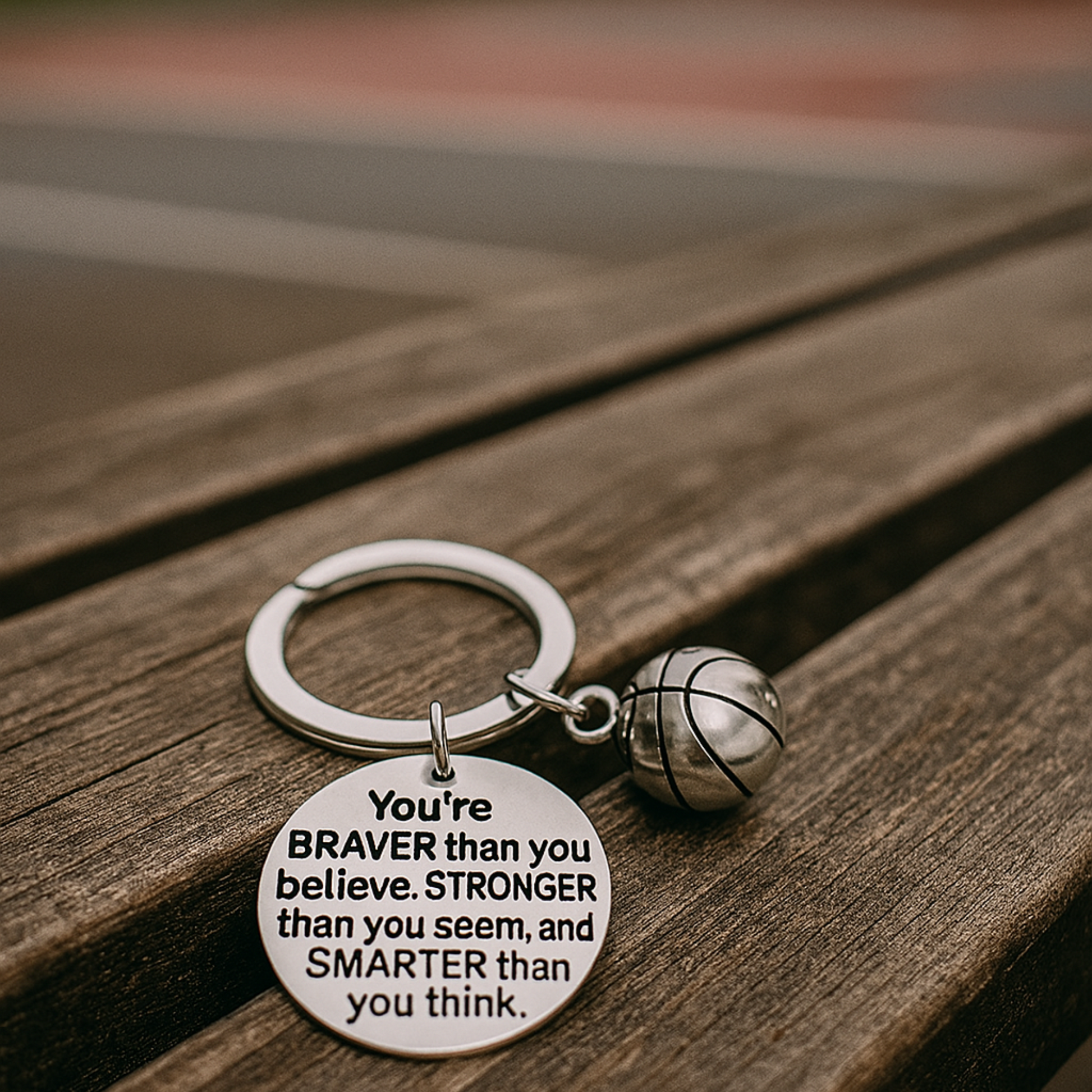 Side angle of engraved basketball keychain placed on wood surface, sporty accessory

