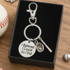 Gift-ready softball keychain placed on black box with baseball prop, perfect sports gift