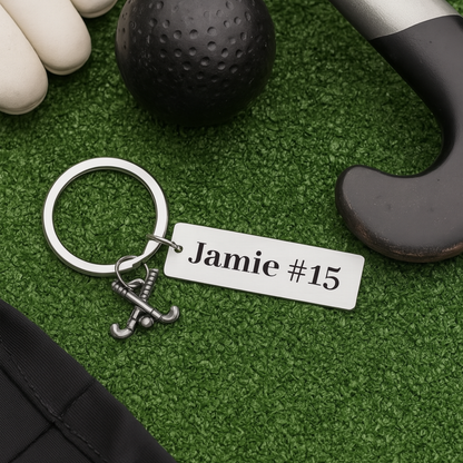 Personalized bar field hockey keychain displayed on turf with stick, ball, and name engraving