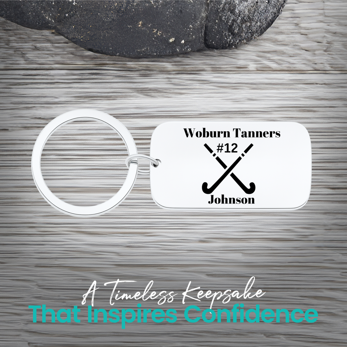Stainless steel field hockey dog tag keychain with crossed sticks and personalized engraving on rustic wood