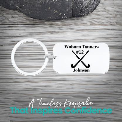 Stainless steel field hockey dog tag keychain with crossed sticks and personalized engraving on rustic wood