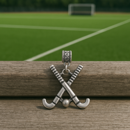 Field hockey crossed sticks charm bead displayed on rustic wood surface