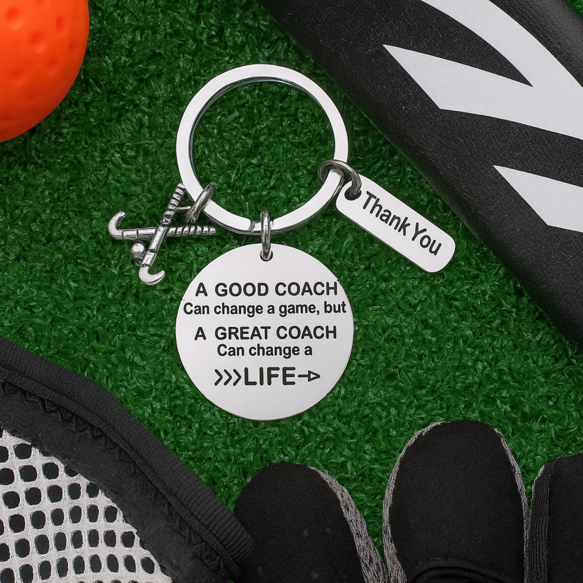 Inspirational field hockey coach keychain with engraved quote displayed on artificial turf