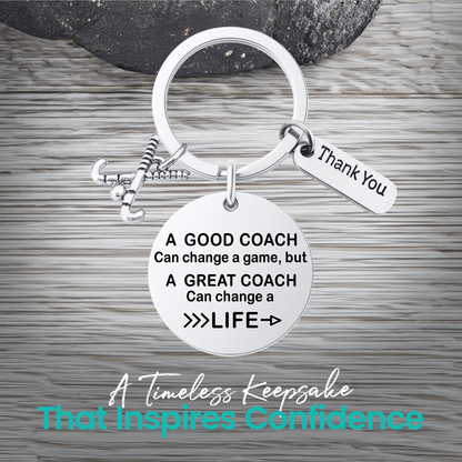 Silver coach keychain with engraved Great Coach Can Change a Life quote on rustic wooden surface