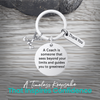 Silver coach keychain with engraved Sees Beyond Your Limits charm on rustic wood background