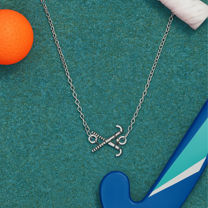 Field hockey charm necklace on teal background with orange ball and blue field hockey stick