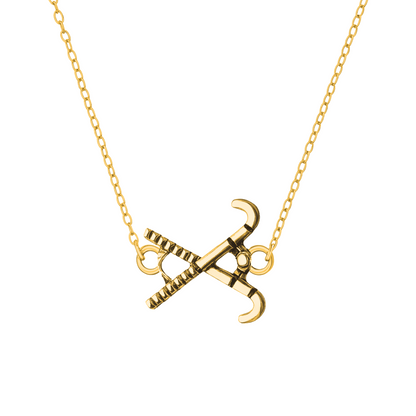 Gold-tone field hockey pendant necklace with stick and ball charm on white background