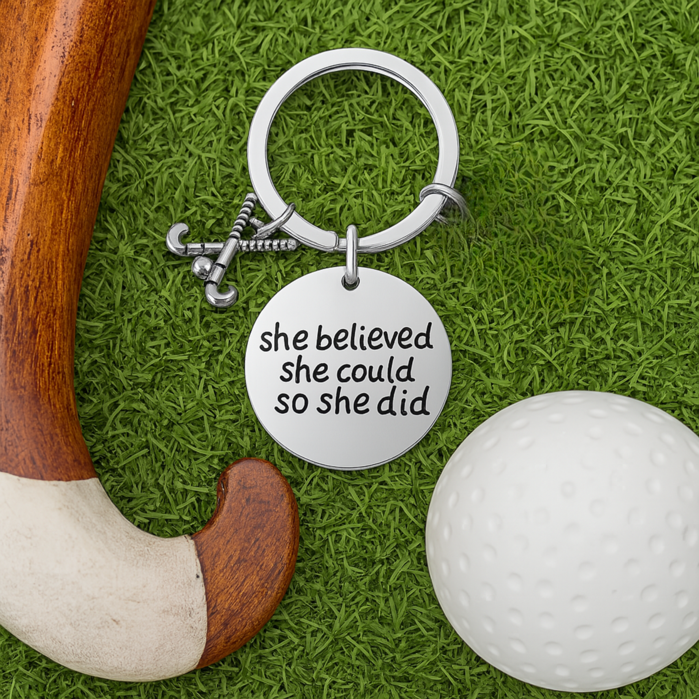 She Believed She Could So She Did field hockey keychain displayed on green artificial turf with hockey ball