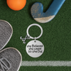 She Believed She Could So She Did field hockey keychain displayed on green artificial turf with hockey ball