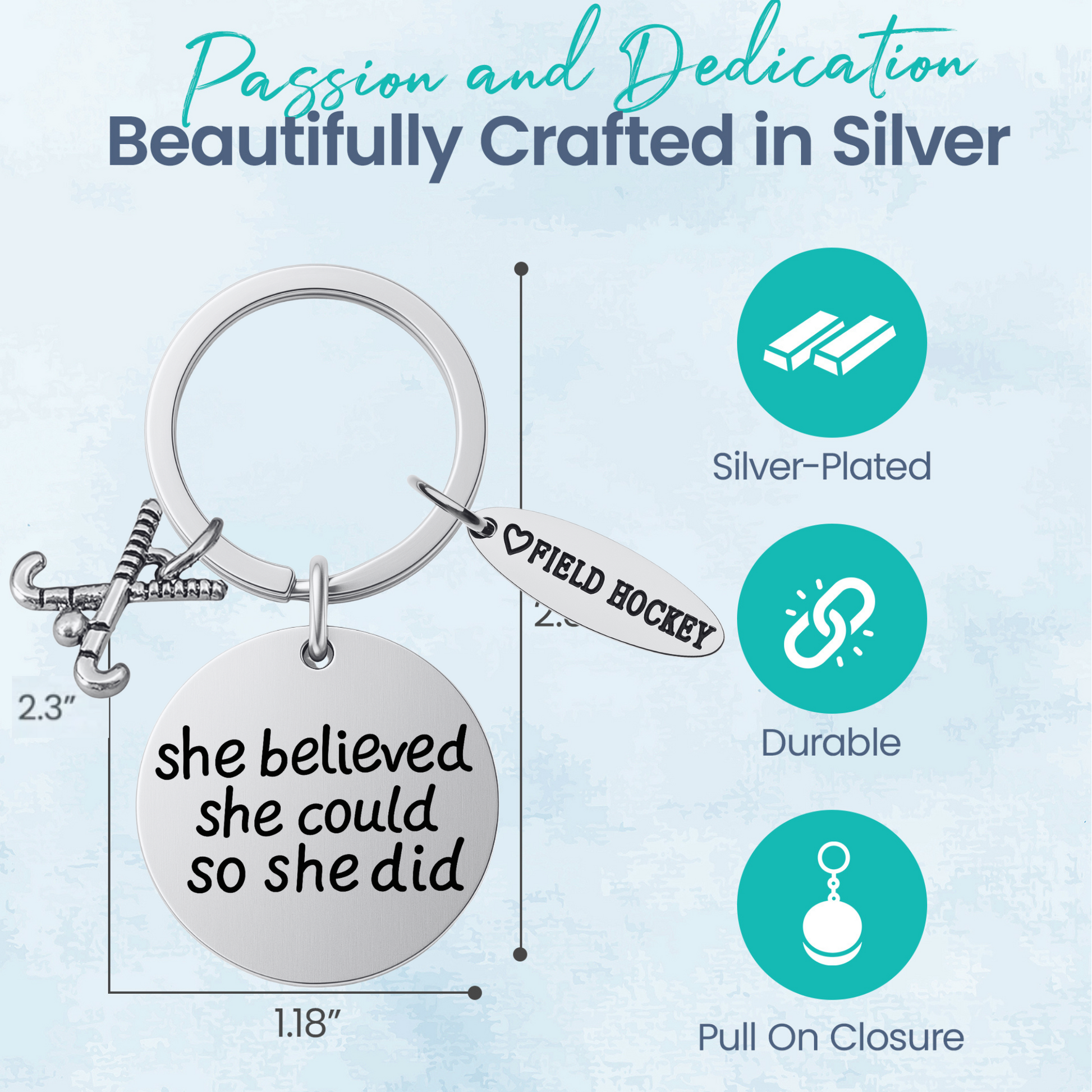 Silver field hockey keychain with She Believed She Could So She Did charm on rustic wooden surface