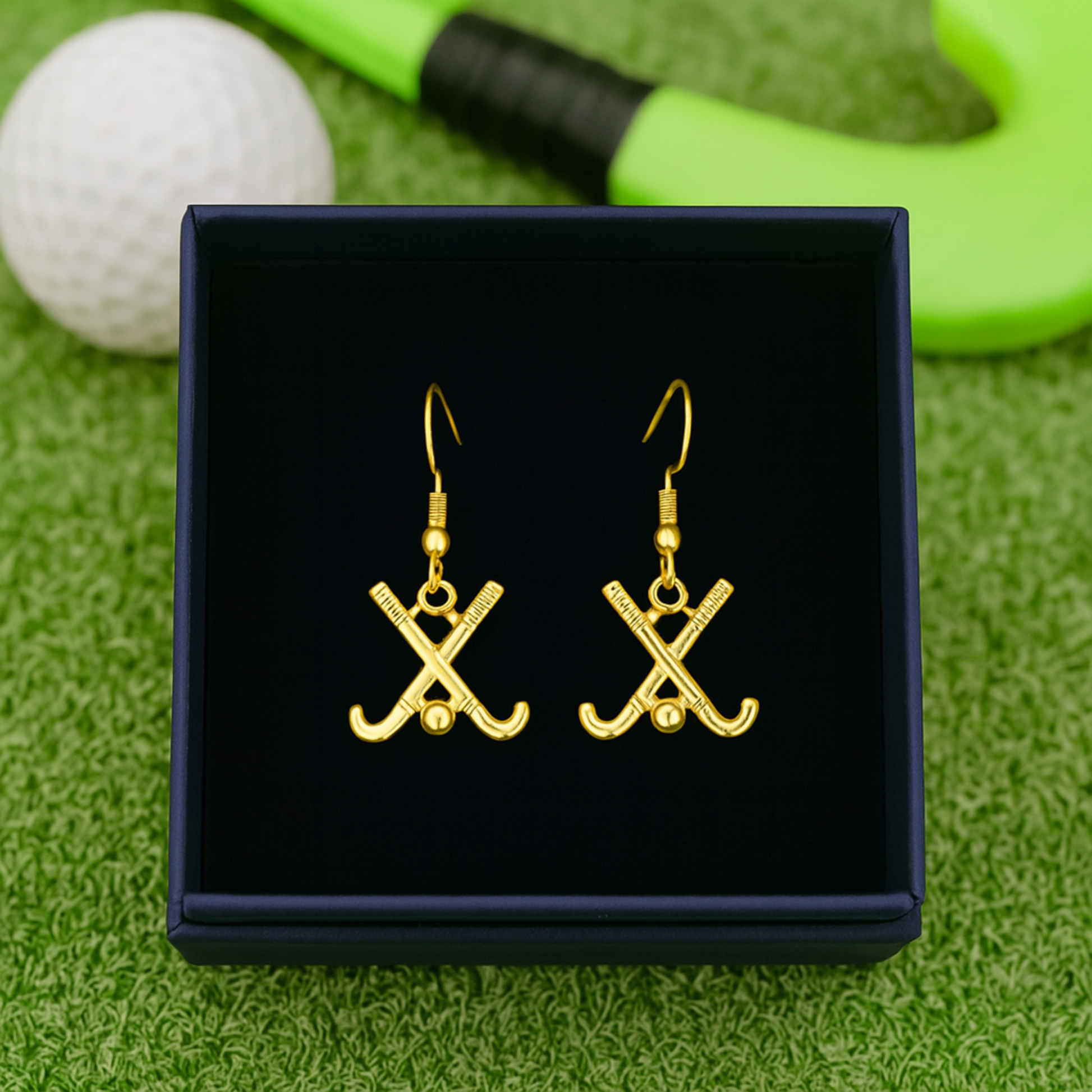 Silver and rose gold field hockey earrings photographed on black stone surface