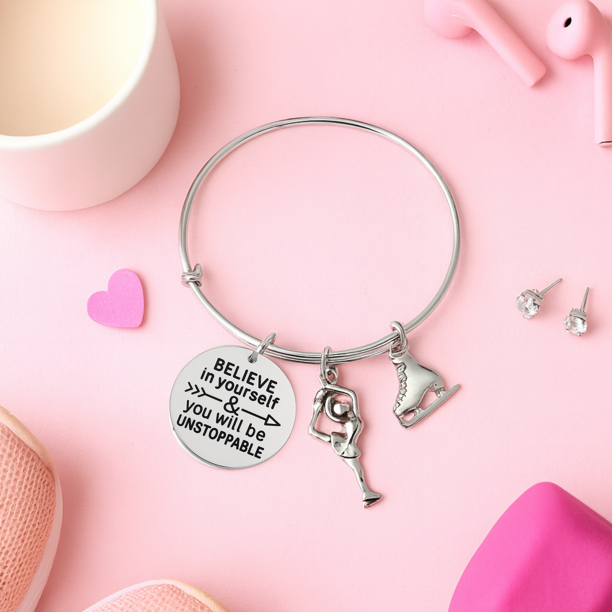 Figure skating bracelet with inspirational charms displayed on pink surface with decorative accents