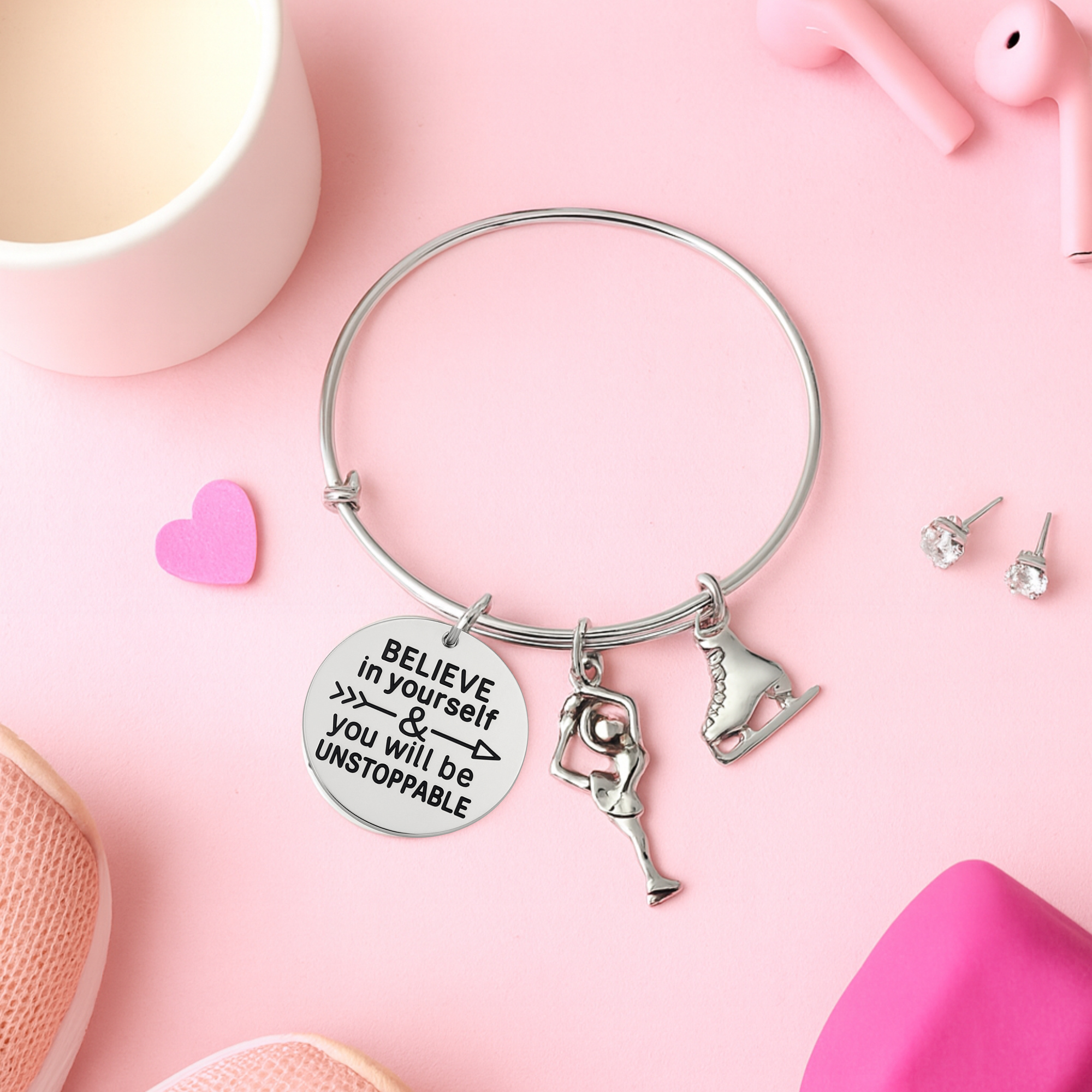 Figure skating bracelet with inspirational charms displayed on pink surface with decorative accents