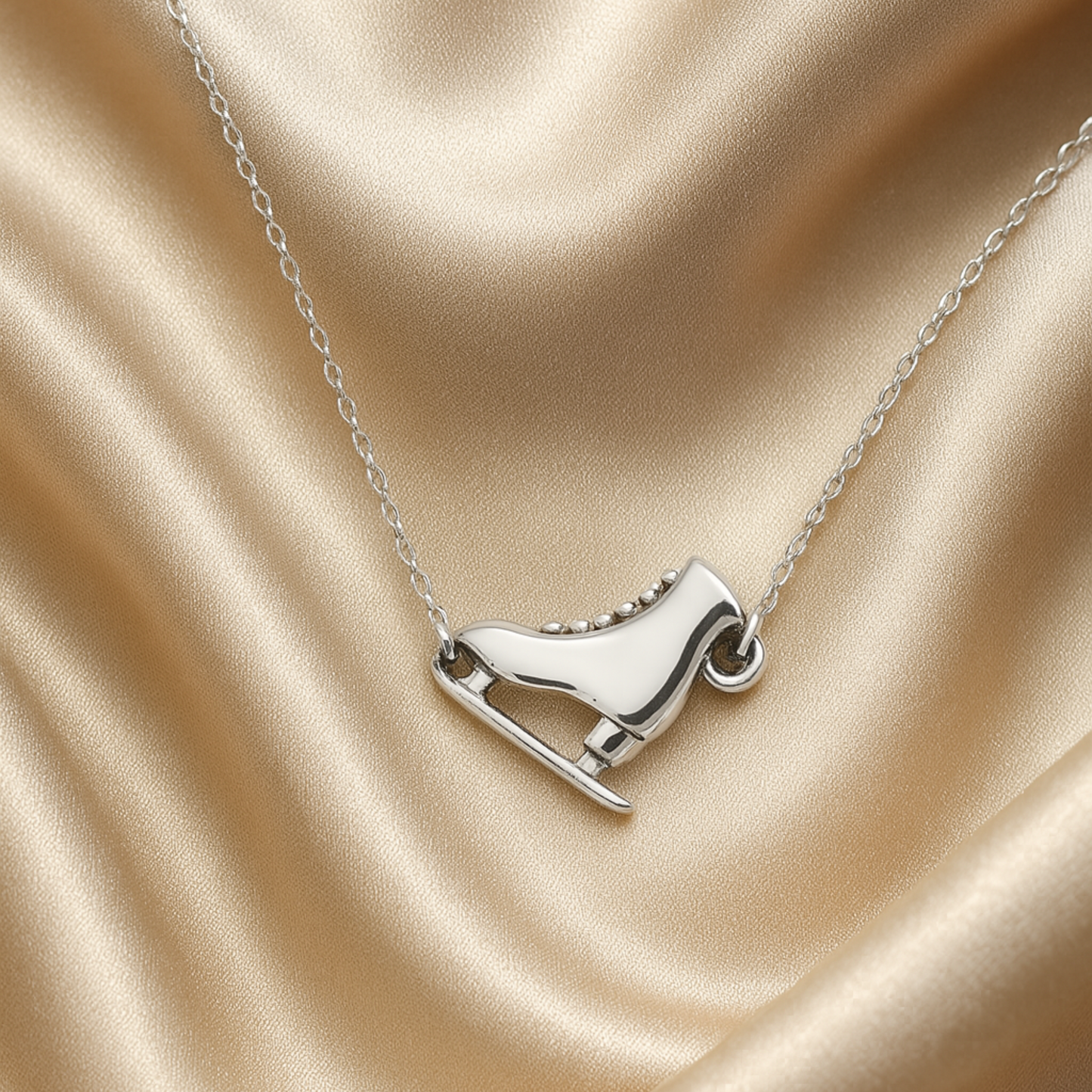 Ice skate charm necklace shown on satin fabric, highlighting elegant jewelry finish