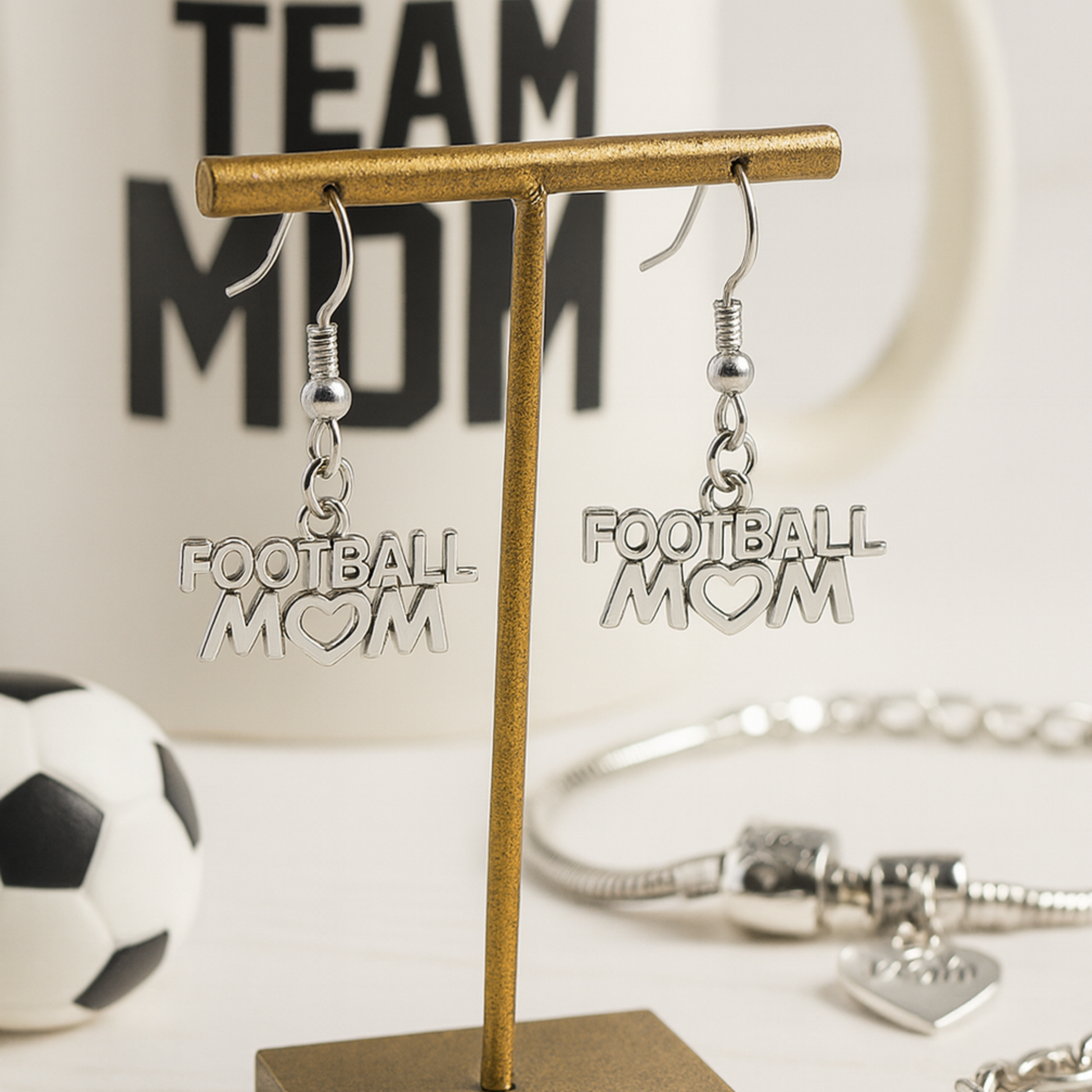 Football Mom earrings displayed with soccer ball and Team Mom sign