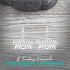 Silver Football Mom earrings displayed on rustic wooden surface
