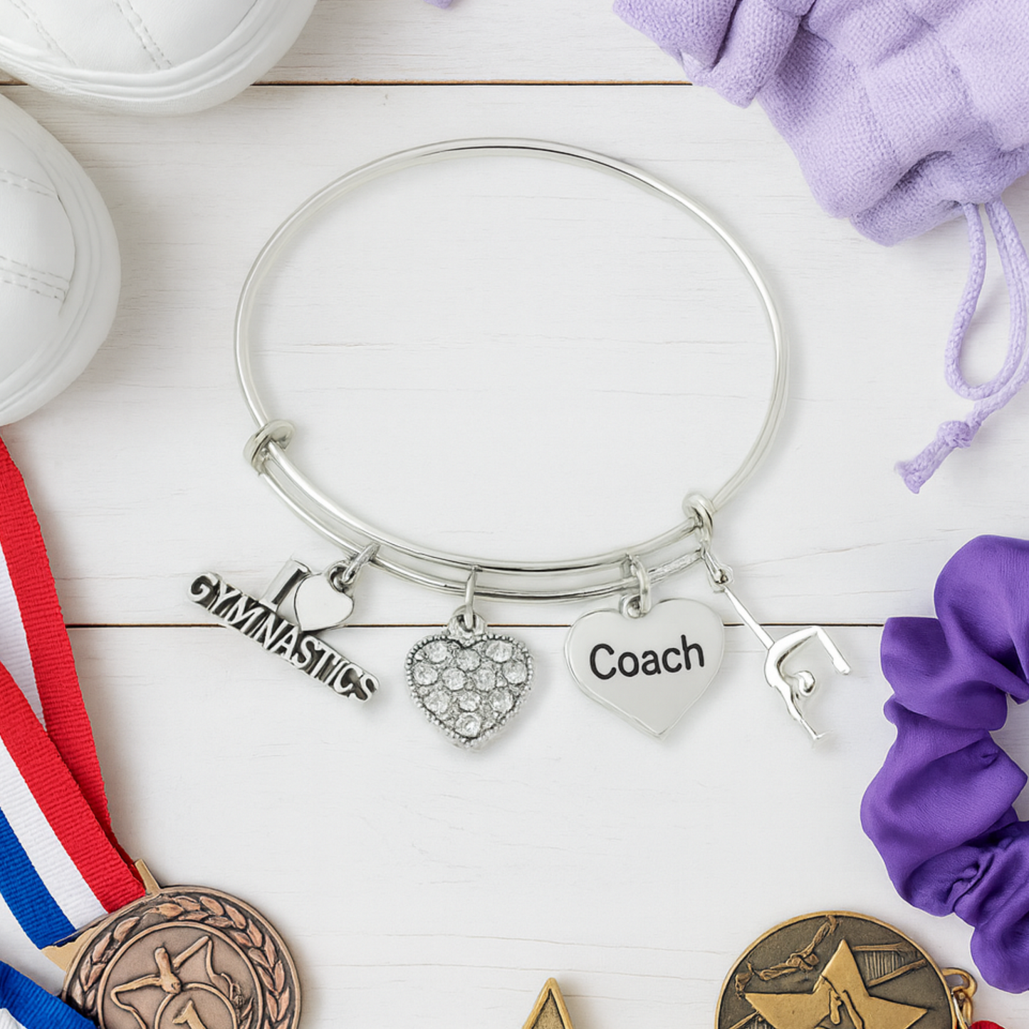 Adjustable gymnastics coach charm bracelet displayed with gymnastics-themed items