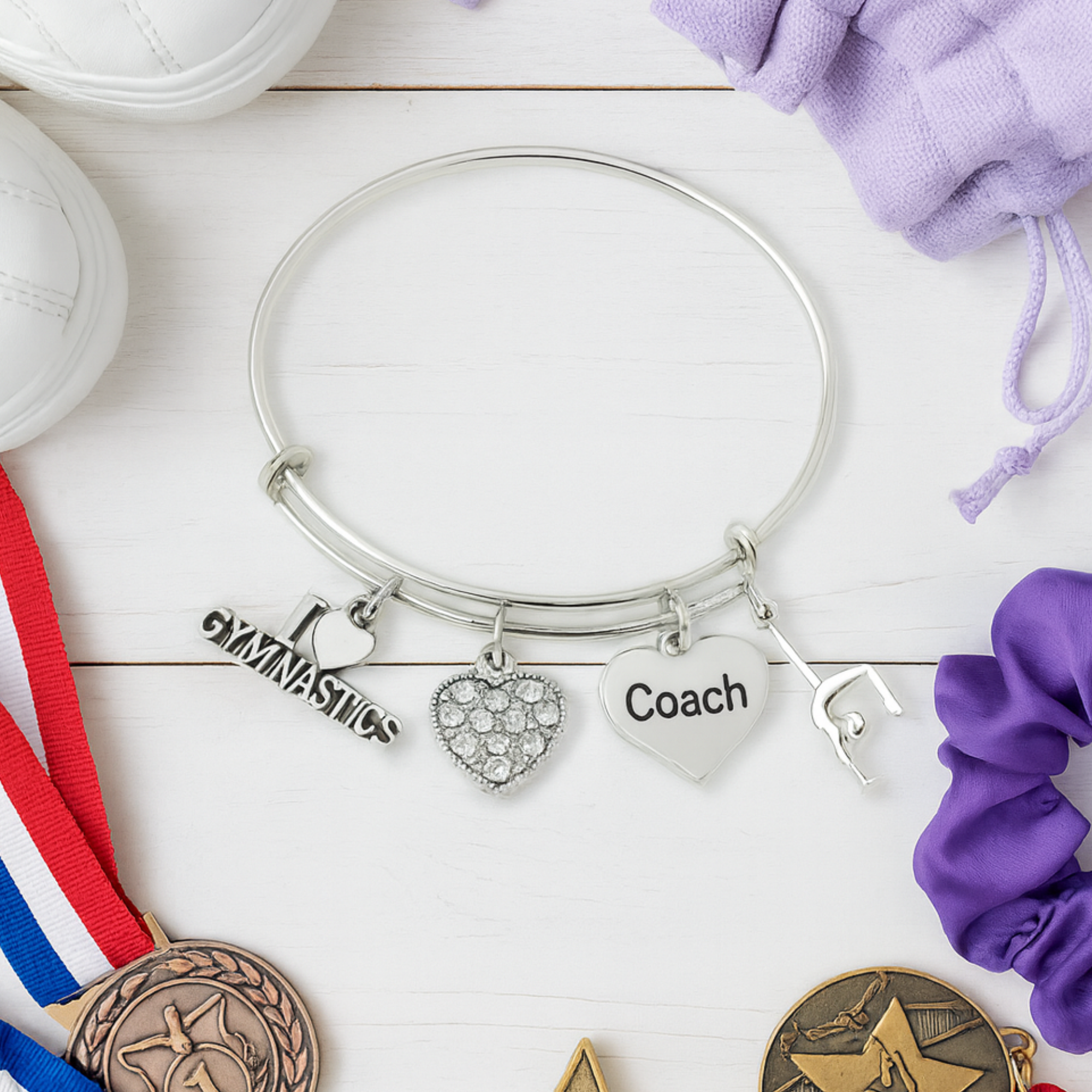Adjustable gymnastics coach charm bracelet displayed with gymnastics-themed items