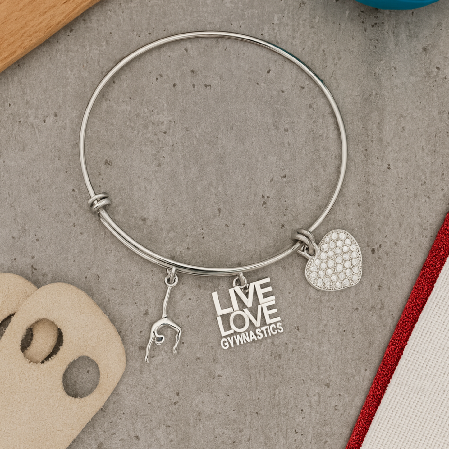 Gymnastics bangle bracelet with silver charms displayed on neutral surface