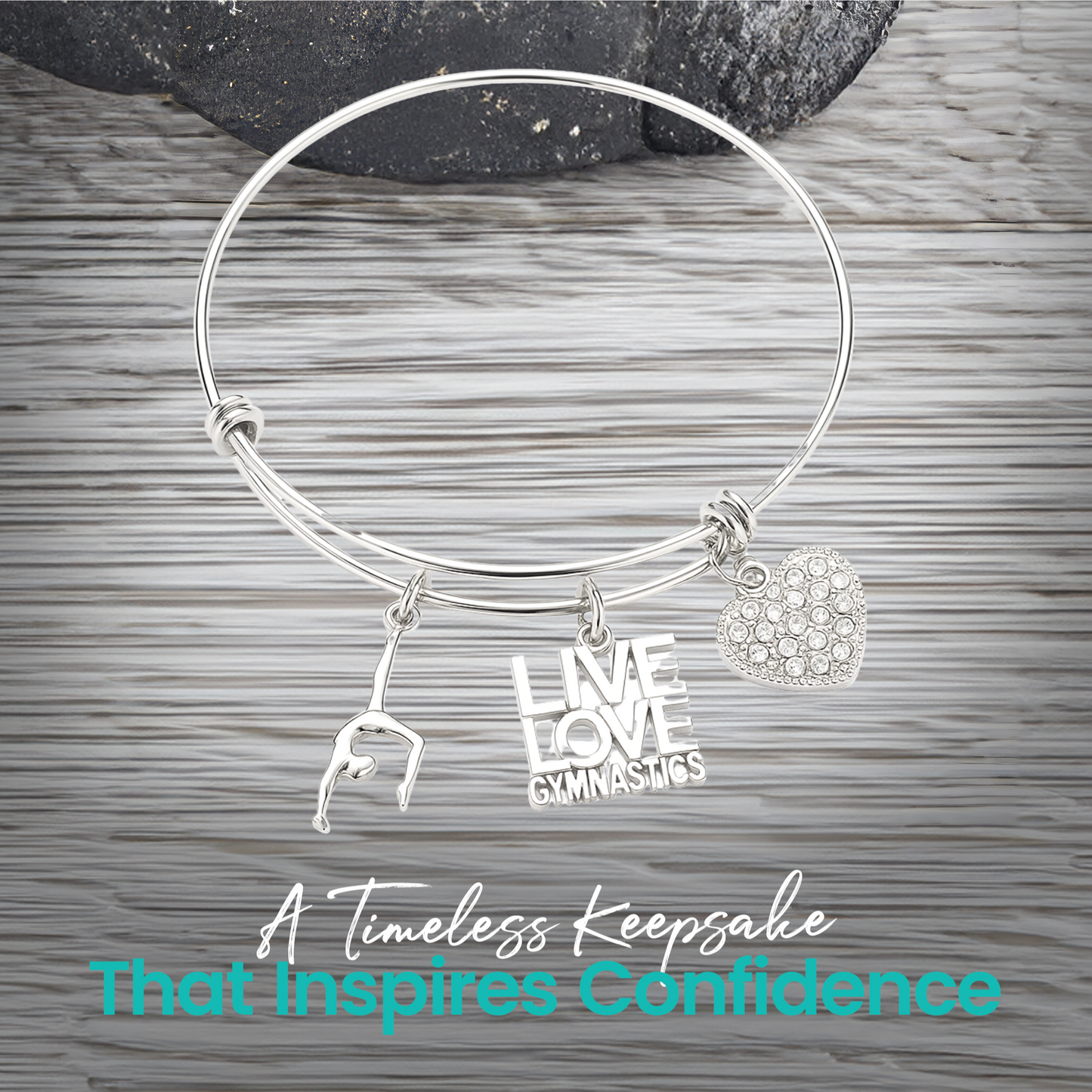 Expandable silver gymnastics bangle bracelet with charms displayed on rustic wooden surface