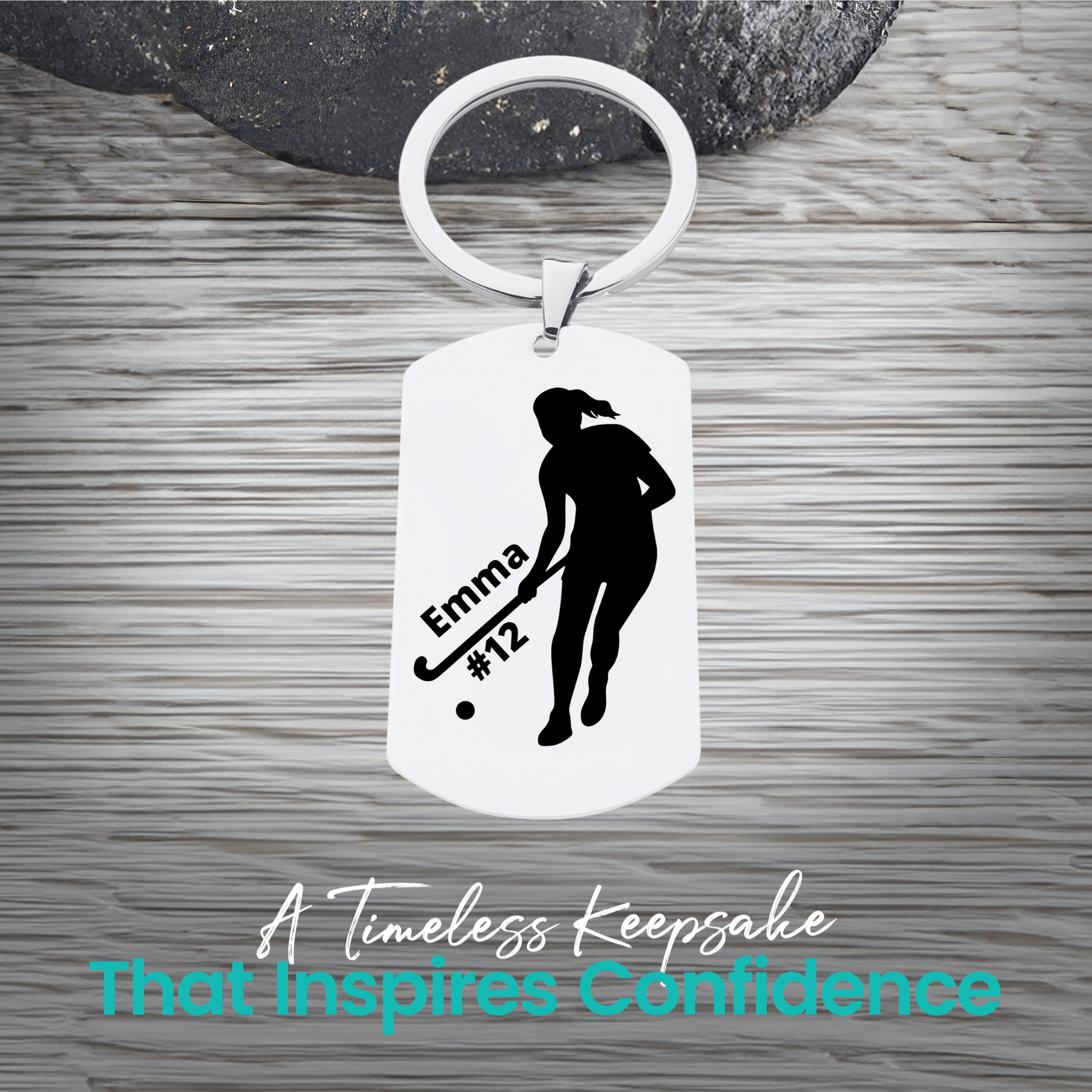 Engraved stainless steel field hockey player silhouette keychain with personalized text on rustic wood surface
