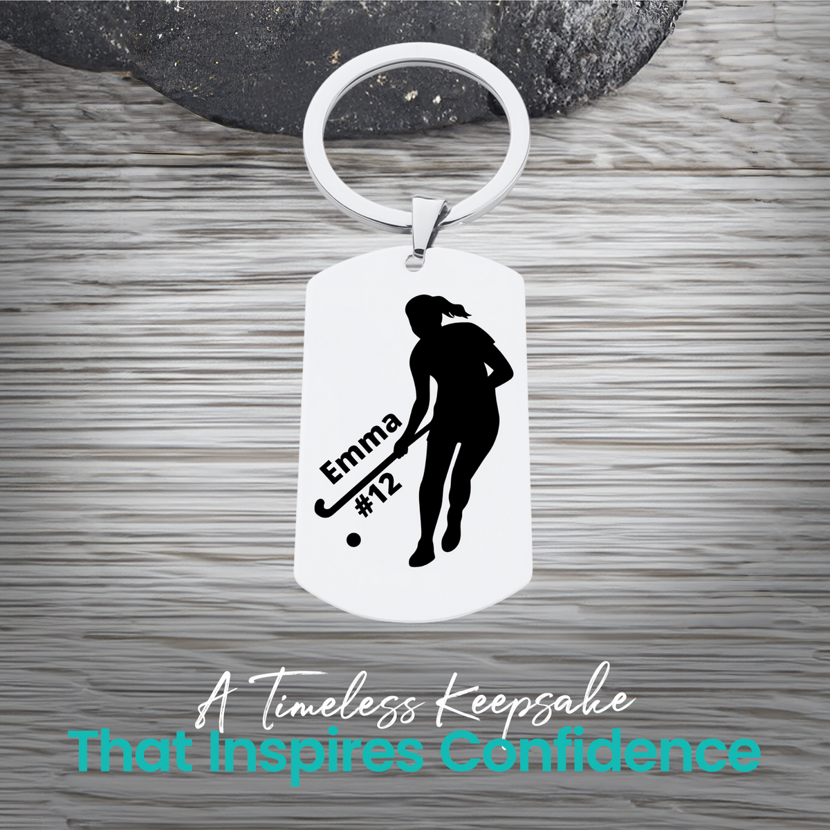 Engraved stainless steel field hockey player silhouette keychain with personalized text on rustic wood surface