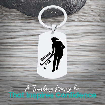 Engraved stainless steel field hockey player silhouette keychain with personalized text on rustic wood surface