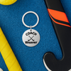 Personalized field hockey coach keychain displayed on yellow and blue sports bag background