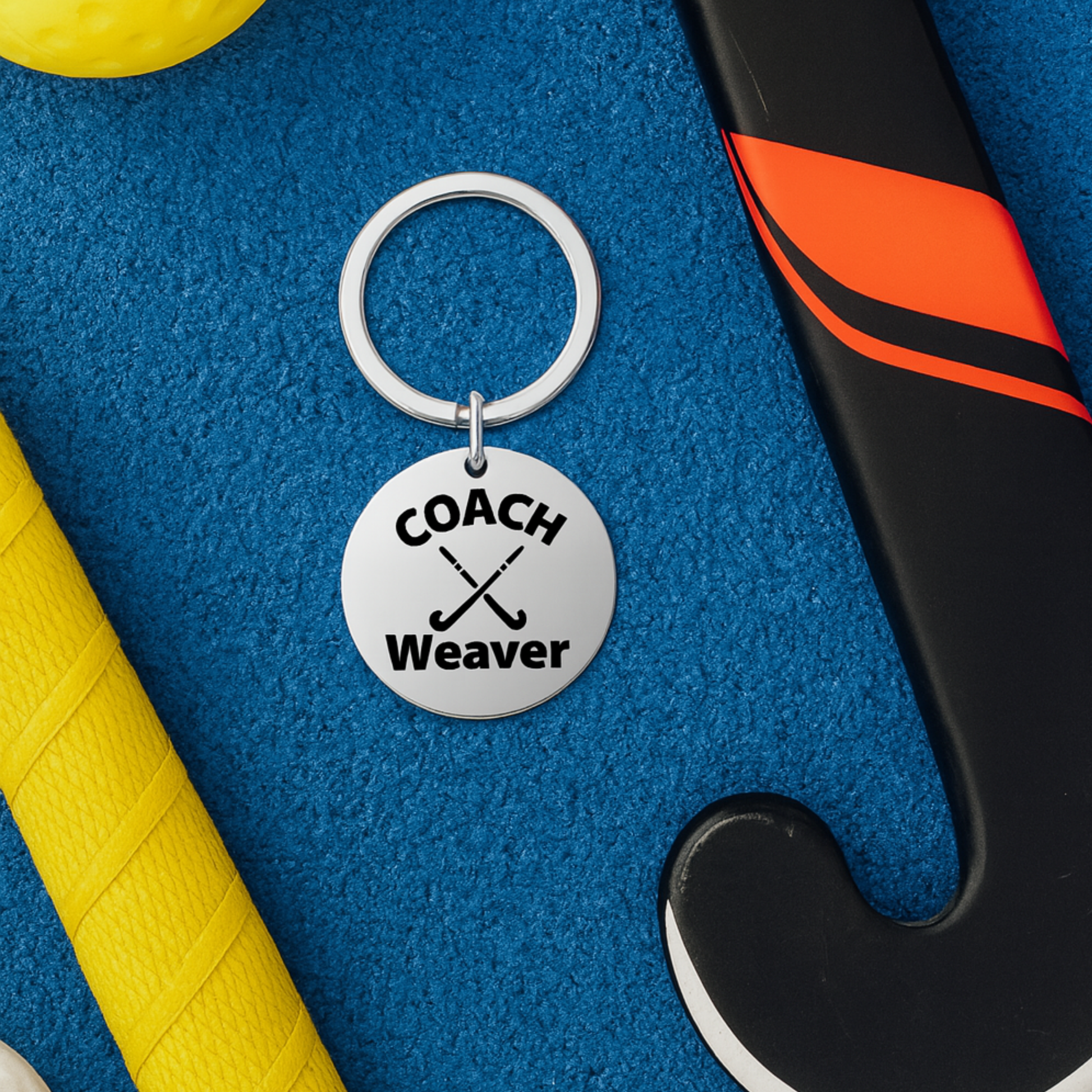 Personalized field hockey coach keychain displayed on yellow and blue sports bag background