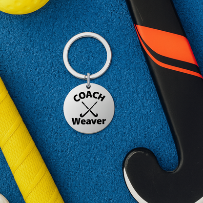 Personalized field hockey coach keychain displayed on yellow and blue sports bag background