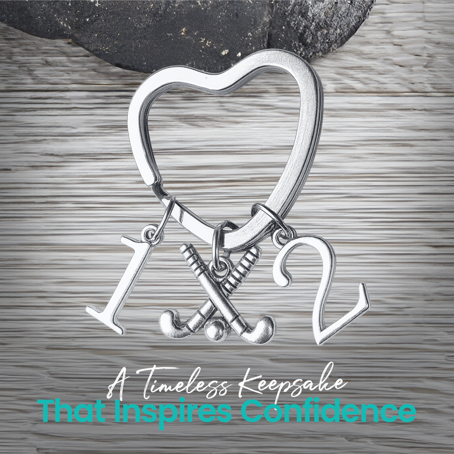 Silver heart-shaped field hockey keychain with crossed sticks and number charms on rustic wood