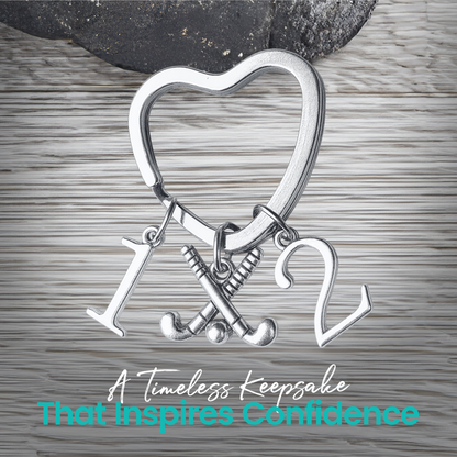 Silver heart-shaped field hockey keychain with crossed sticks and number charms on rustic wood