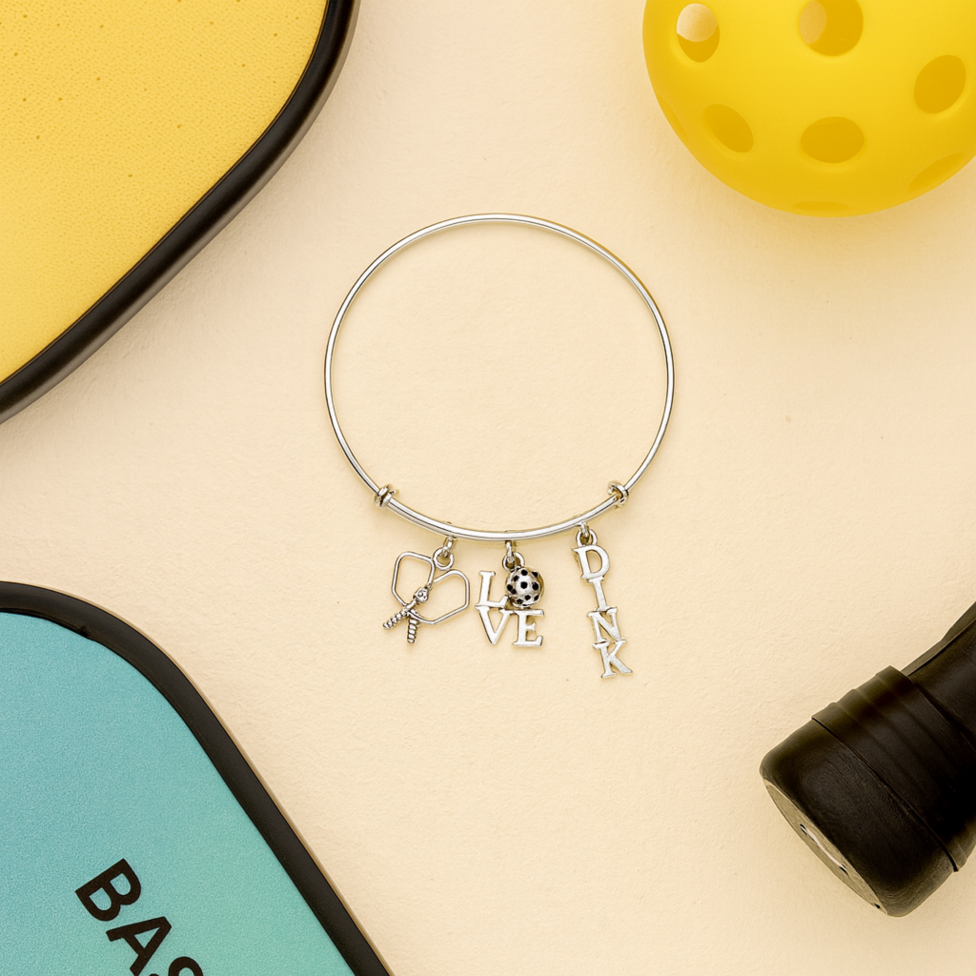 Pickleball charm bracelet with paddle, ball, and LOVE charms displayed on bright yellow background