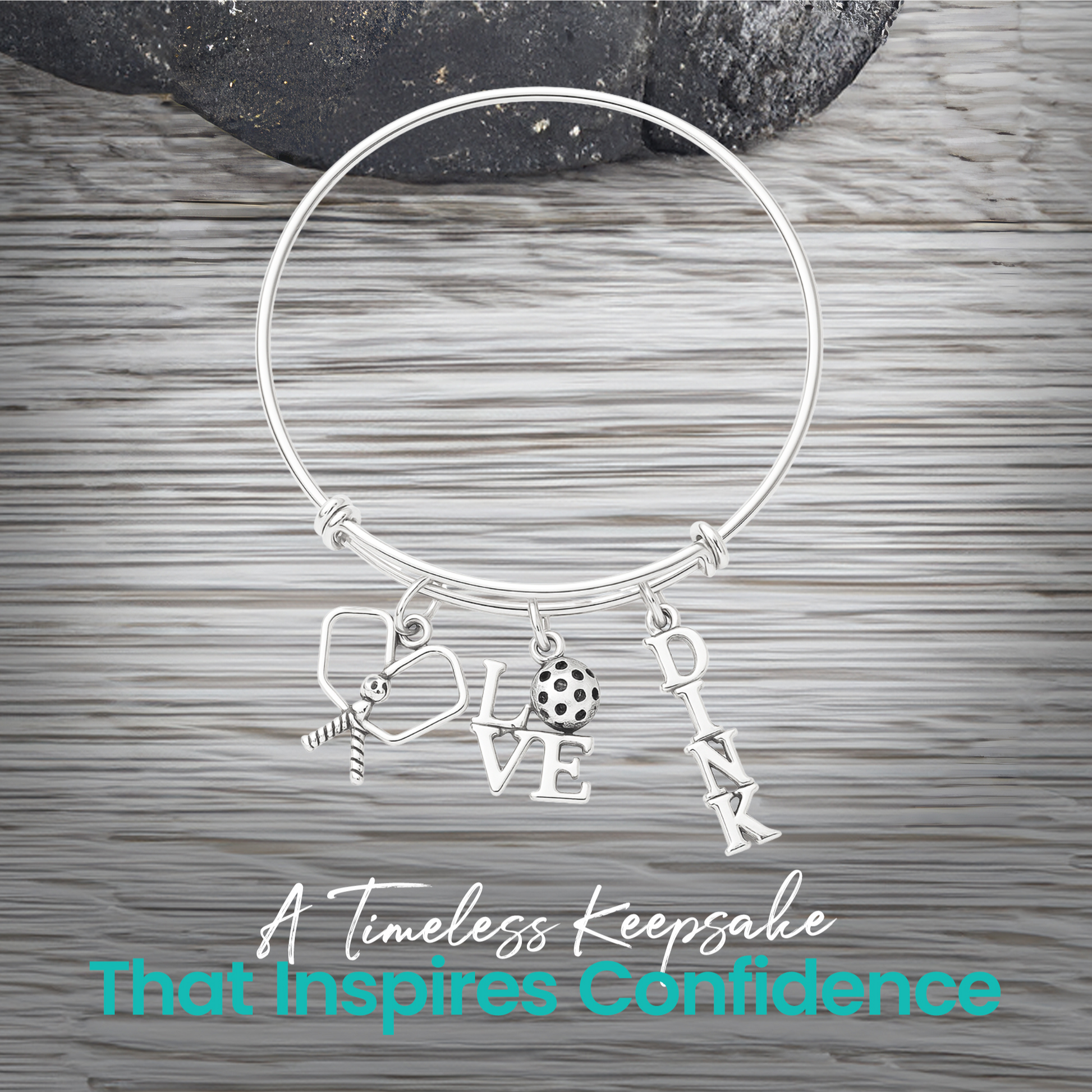 Silver pickleball paddle and ball charm bracelet displayed on rustic wood background