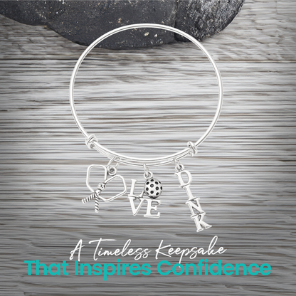 Silver pickleball paddle and ball charm bracelet displayed on rustic wood background