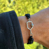 Lifestyle image: black bracelet with silver paddle charm worn on wrist outdoor
