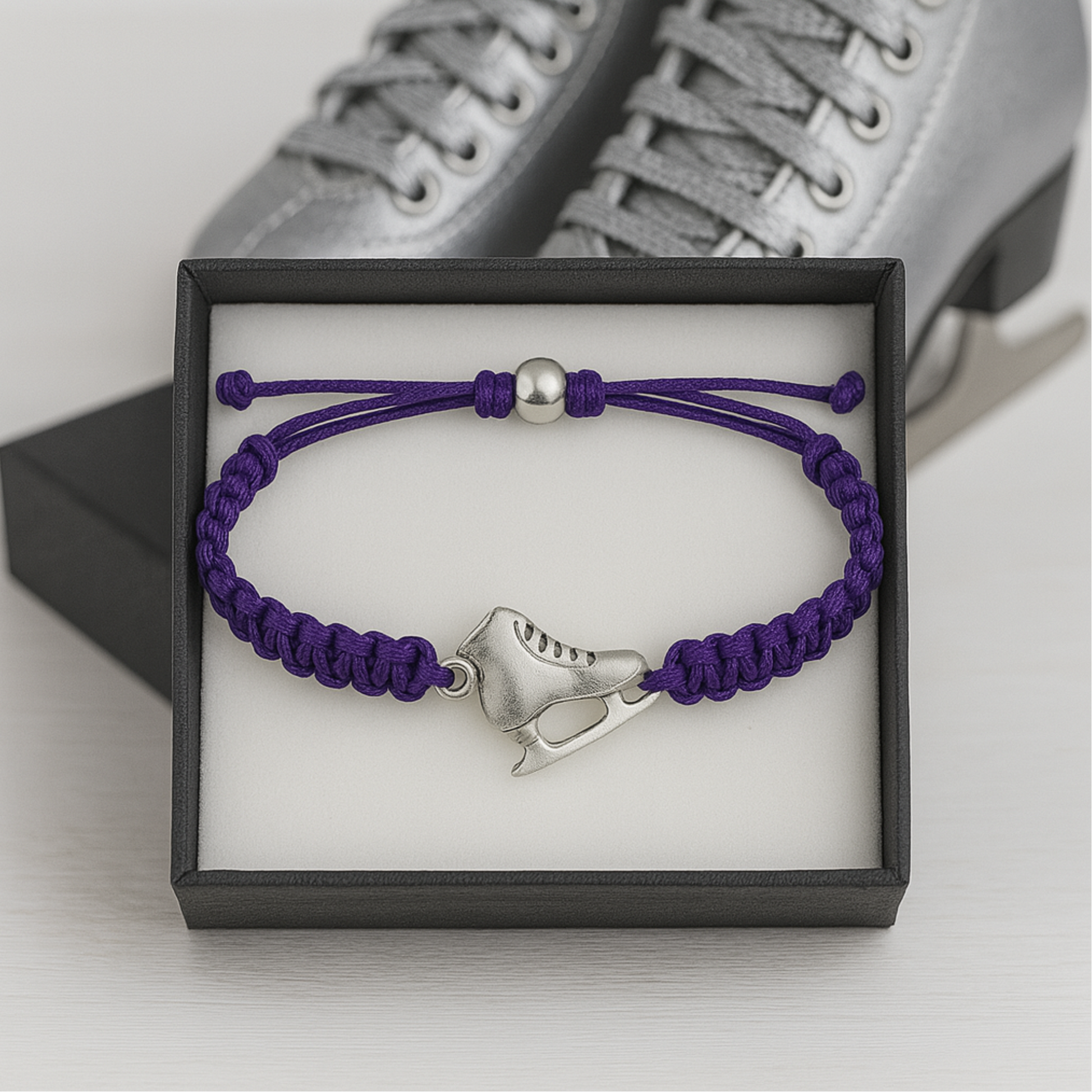 Dark purple figure skating bracelet displayed next to skates in gift box