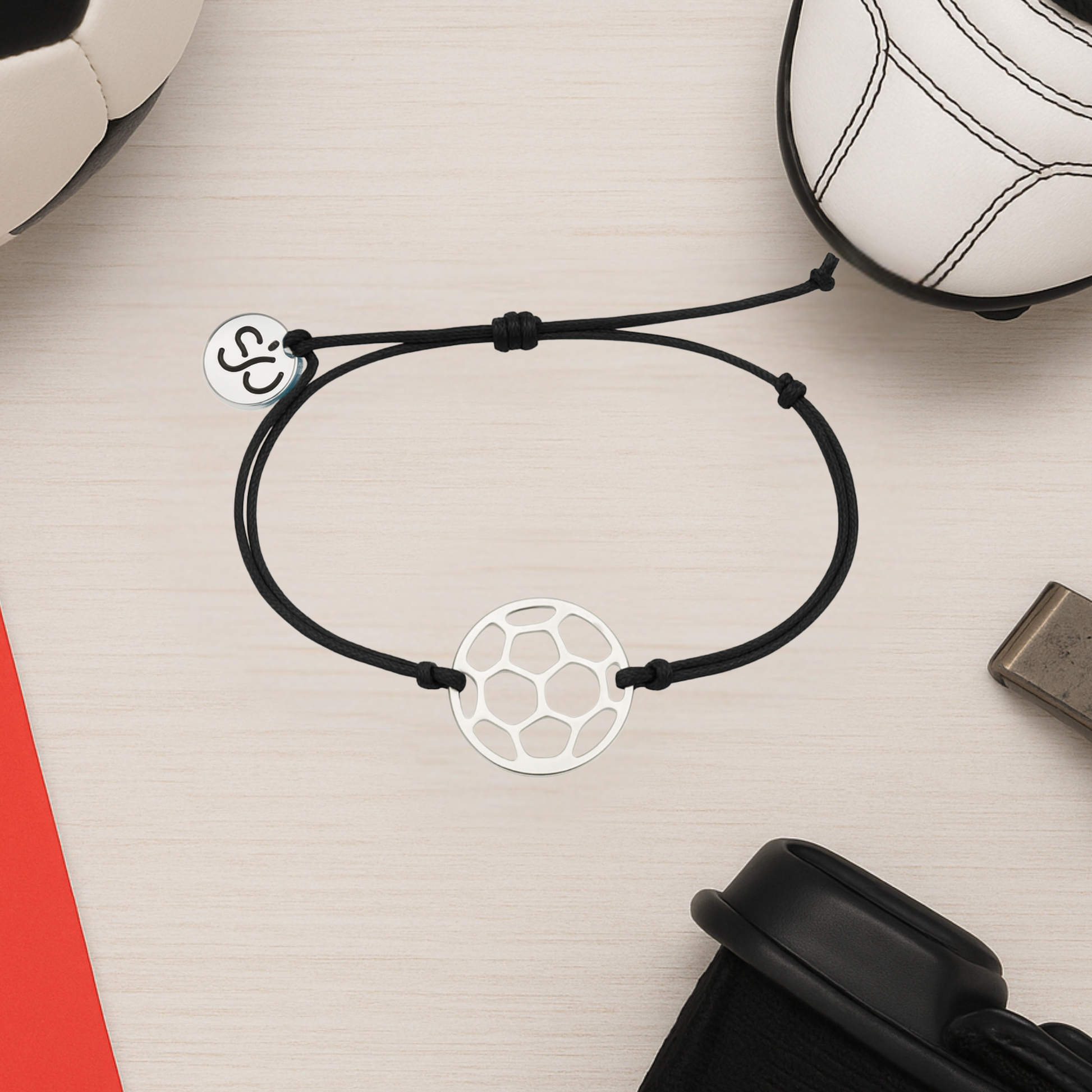 Black soccer rope bracelet with stainless steel charm styled with soccer accessories