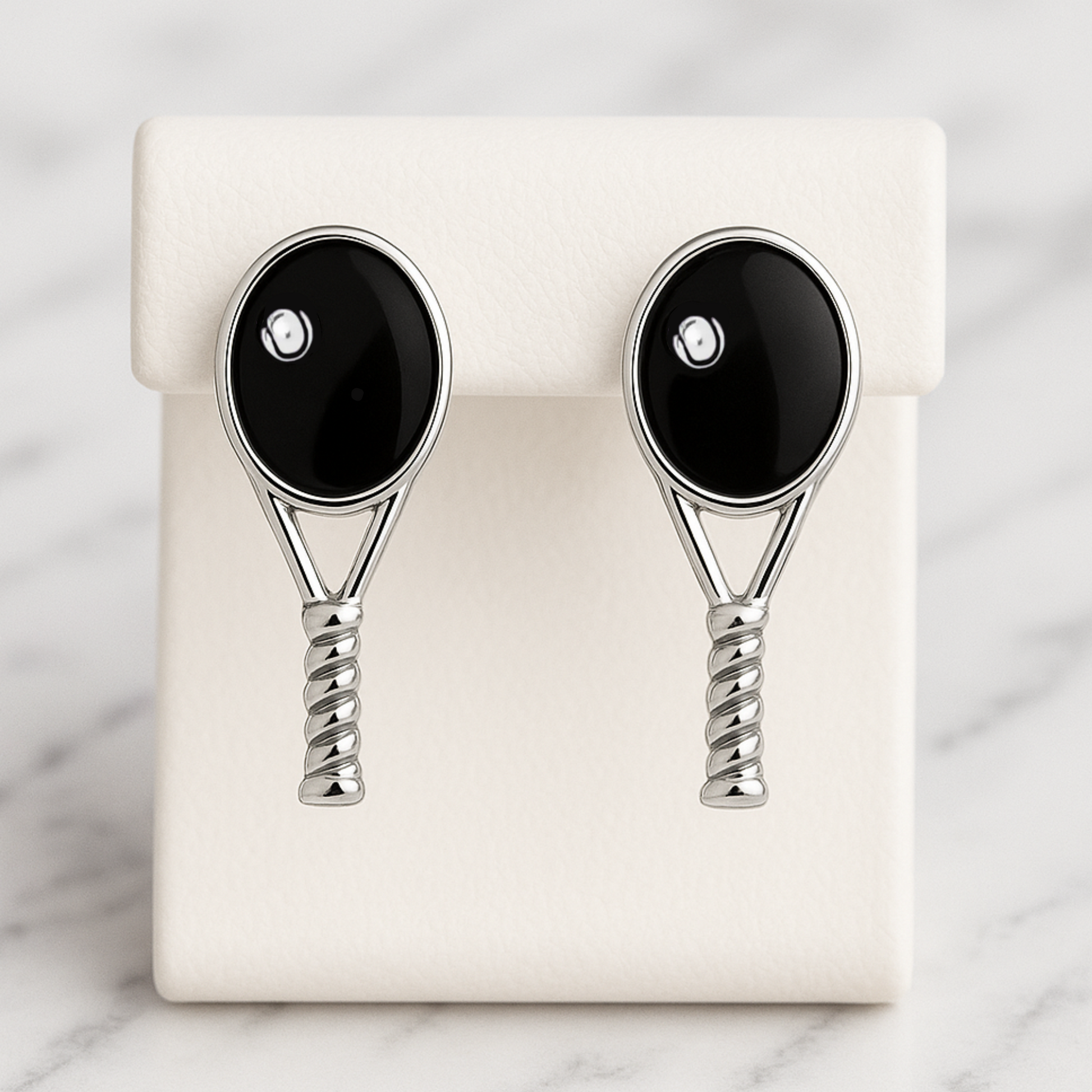Black tennis racquet stud earrings displayed on earring card