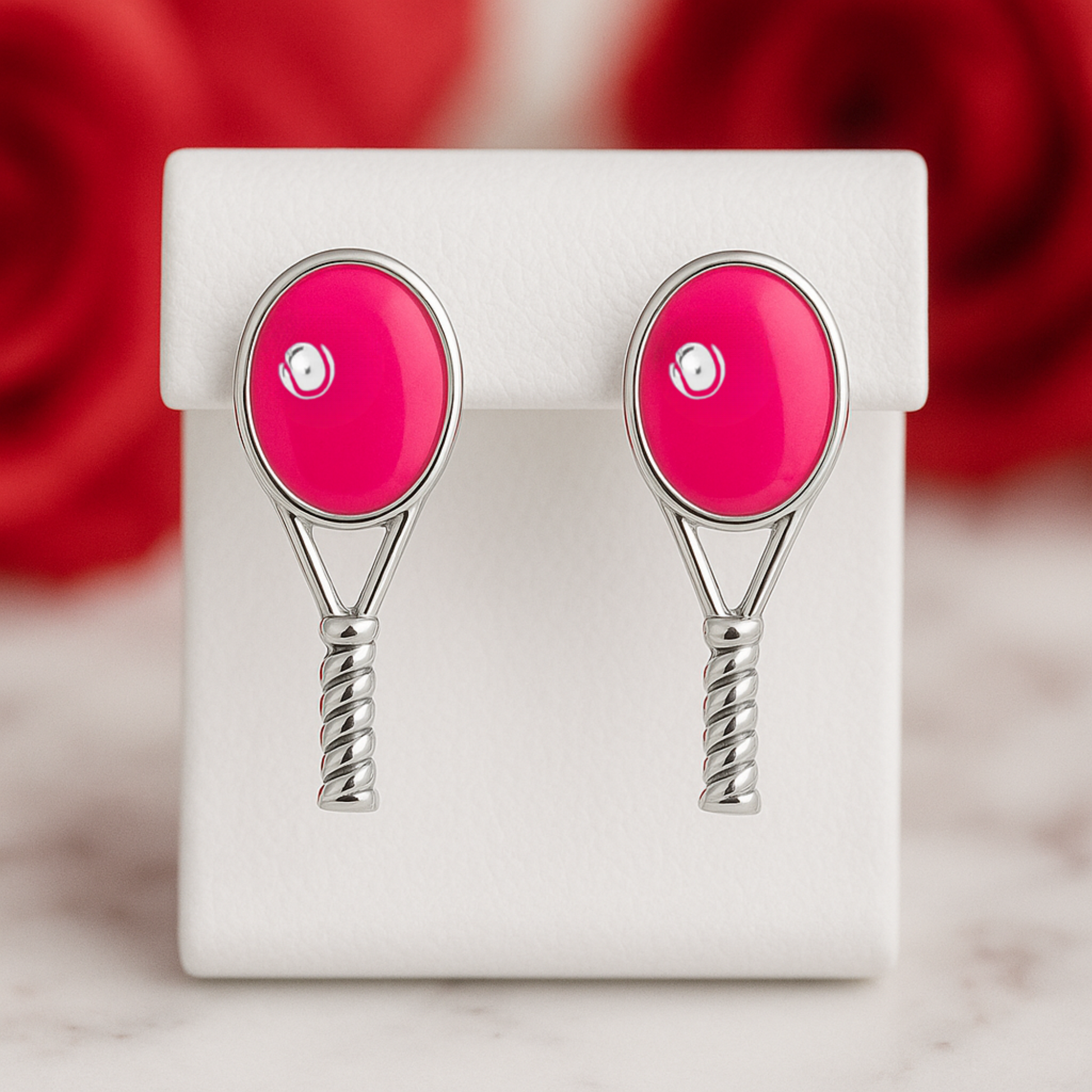 Bright pink tennis racquet stud earrings displayed for gift giving