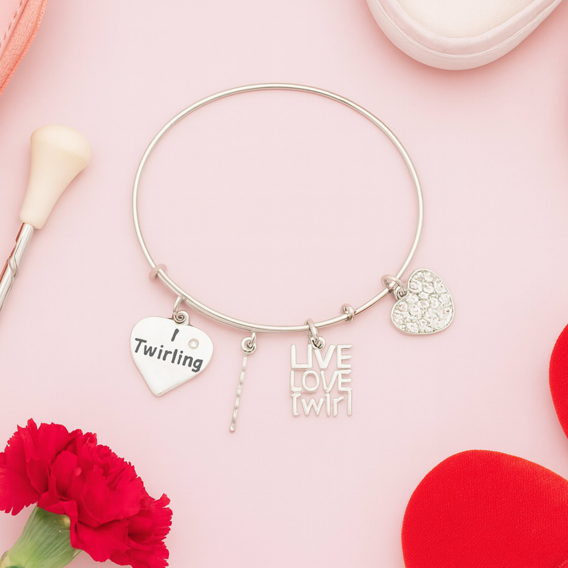Twirling charm bracelet for baton twirlers displayed on pink background with decorative flowers
